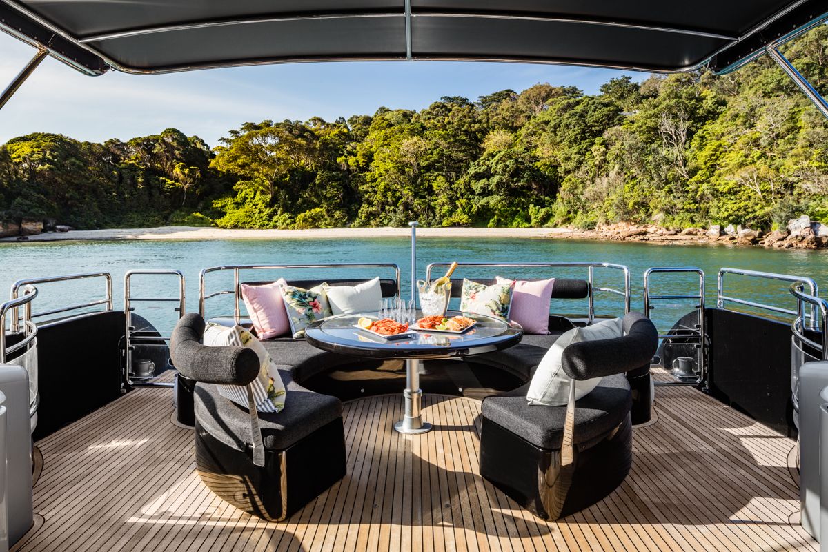 Aft deck dining area set with seafood and champagne, overlooking a secluded harbour beach