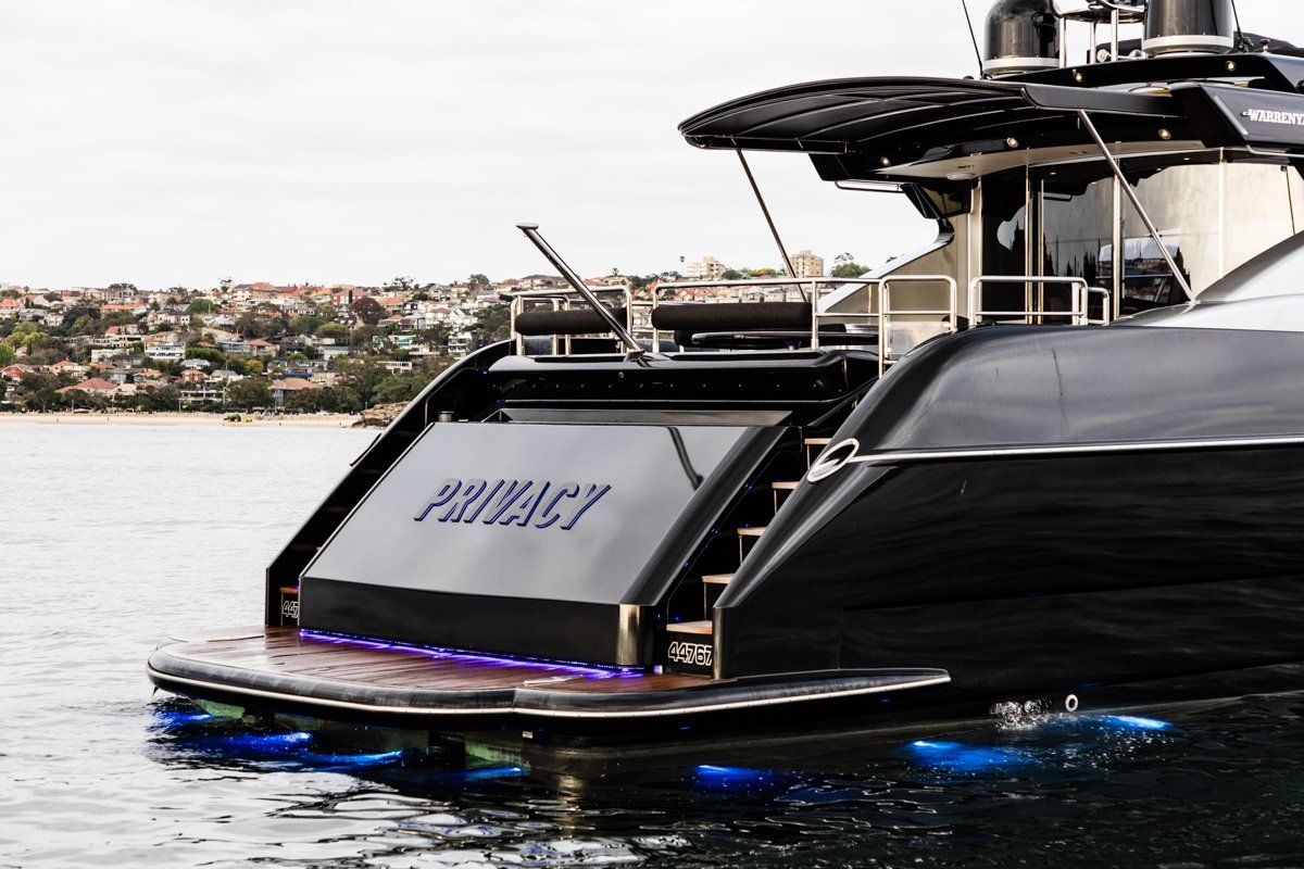 The stern of PRIVACY with its name lit in blue